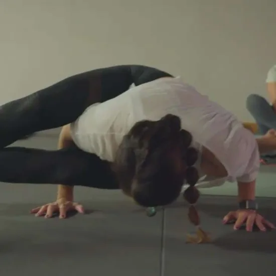Socia haciendo una postura de equilibrio sobre brazos en la clase de yoga de Colen, en Logroño, con compañeros sonriendo al fondo