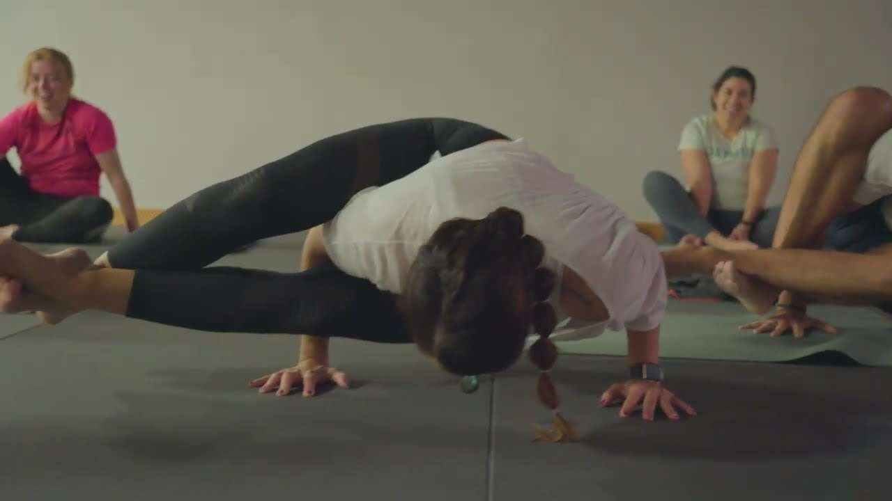 Socia haciendo una postura de equilibrio sobre brazos en la clase de yoga de Colen, en Logroño, con compañeros sonriendo al fondo