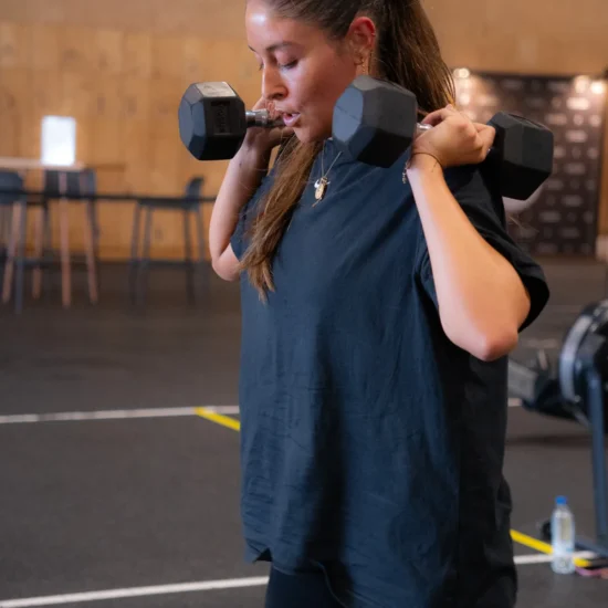 Socia de CrossFit Colen trabajando el press de hombro con mancuerna en la clase de fuerza BUILD, en Logroño