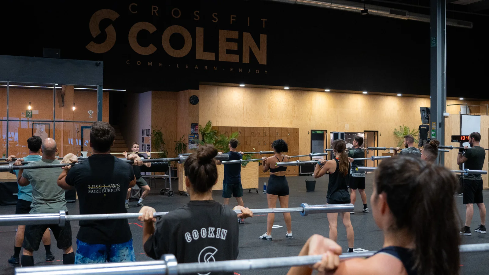Clase de CrossFit en el box de Colen, en Logroño, con el grupo haciendo sentadillas con barra bajo el rótulo de Colen